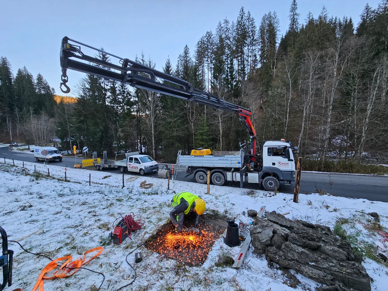 Kran-Lkw und Mitarbeiter auf einer Winterbaustelle